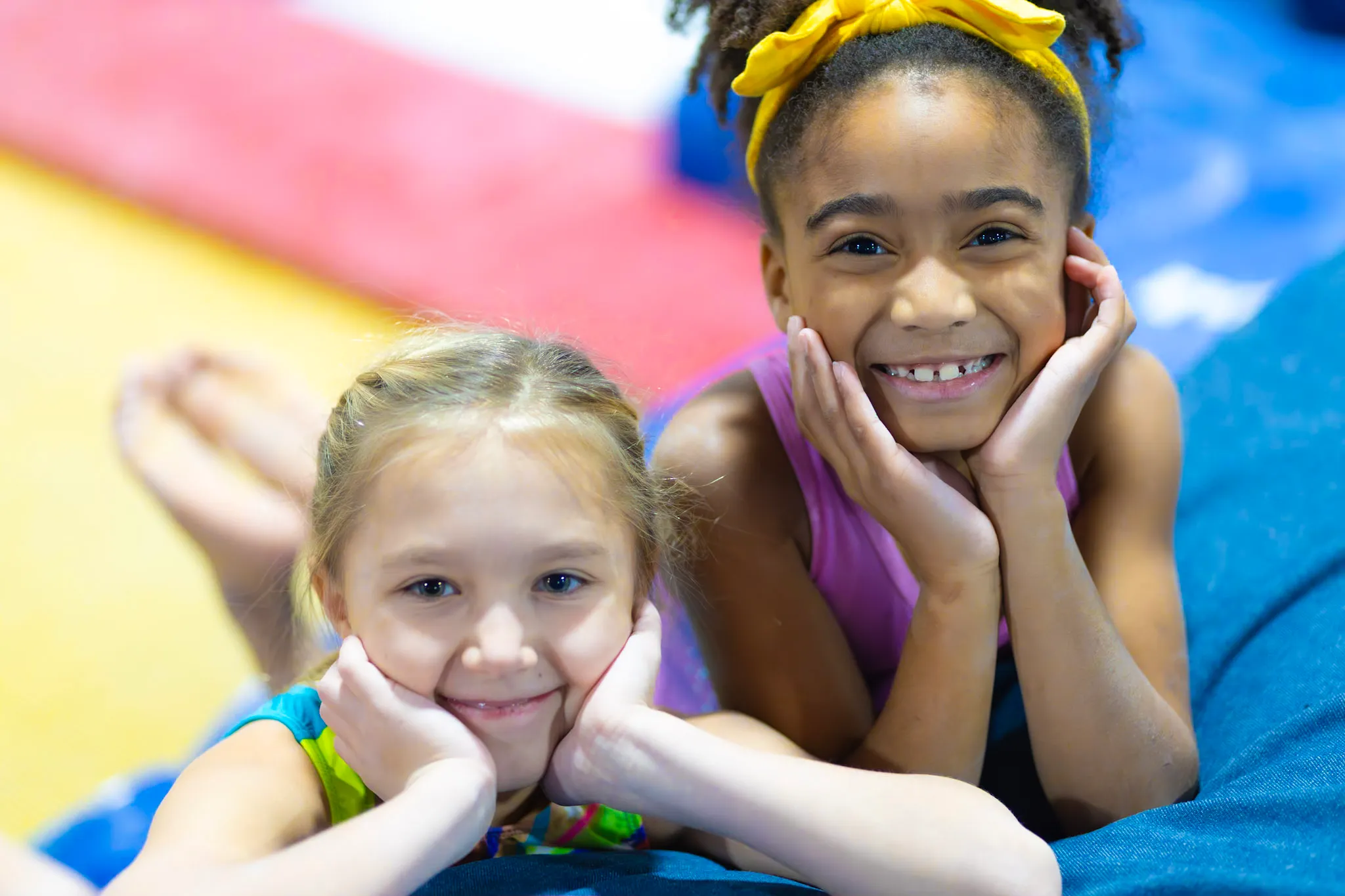 Two girls resting their chins on their hands on the floor mat