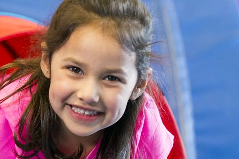 Girl crawling through a tunnel at homeschool open gym